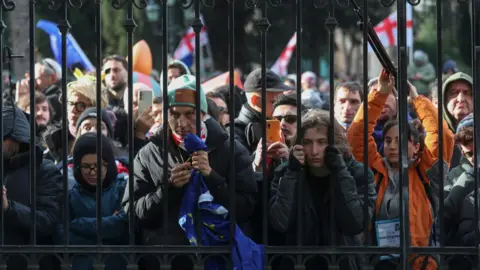 Reuters People listen to outgoing Georgian President Salome Zourabichvili's statement outside the Orbeliani Palace in Tbilisi, Georgia, 29 December 2024