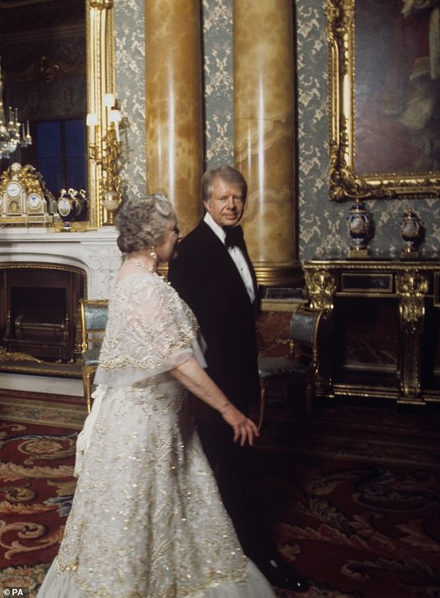 The Queen Mother walks with President Jimmy Carter, seen right, in the Blue Drawing Room at Buckingham Palace. The Royal Family entertained seven world leaders during a dinner