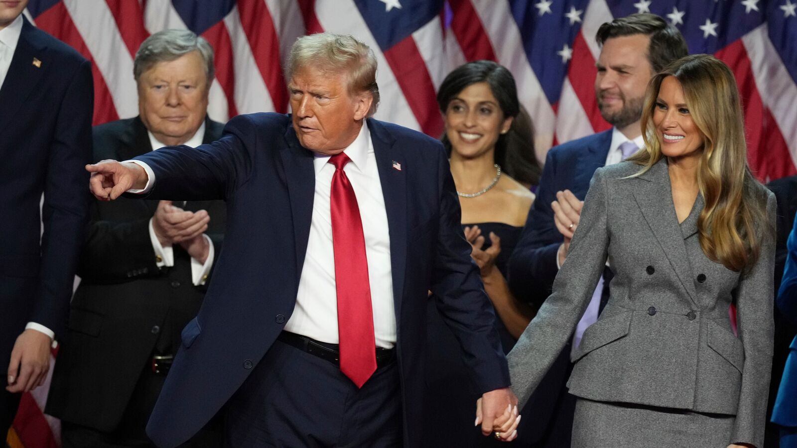 US President-elect Donald Trump holds hands with former first lady Melania Trump after speaking to supporters at the Palm Beach County Convention Center, 