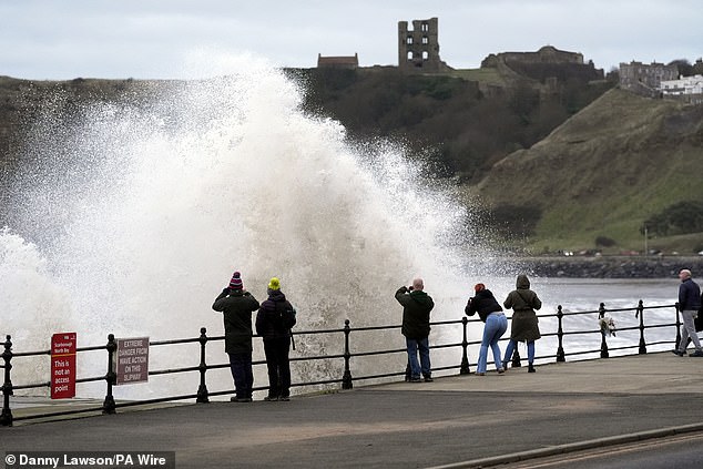 People watch waves crashing into Scarborough in North Yorkshire this afternoon