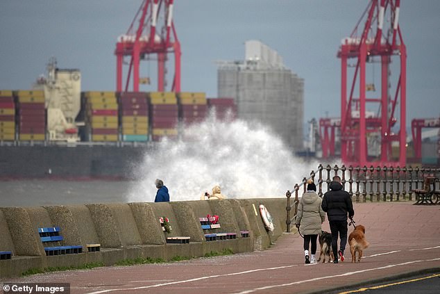 People watch the waves being whipped up by the wind in New Brighton, Merseyside, today