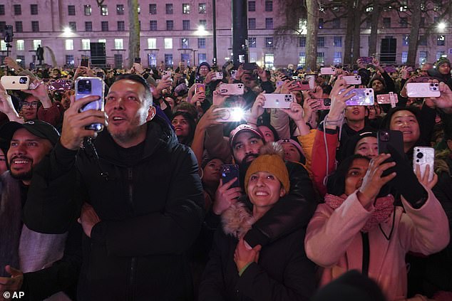 People look up, watch and take photos as fireworks light up the sky around the London Eye to celebrate the New Year in London, January 1, 2025