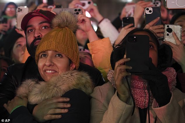 Crowds watch from the north bank of the River Thames as fireworks light up the sky around the London Eye