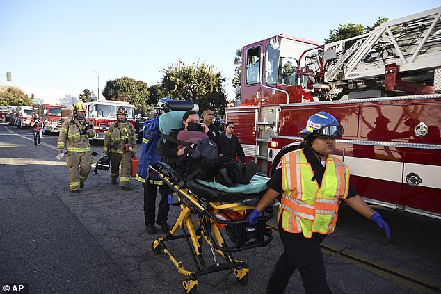 A woman is carried on a stretcher near the site of a plane crash in Fullerton, California