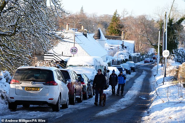 A car is driven through snow in Balerno, Edinburgh, on Friday as the wintry weather continues