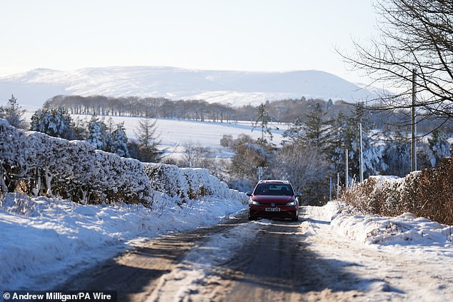 A car is driven through snow in Balerno, Edinburgh, on Friday as the wintry weather continues