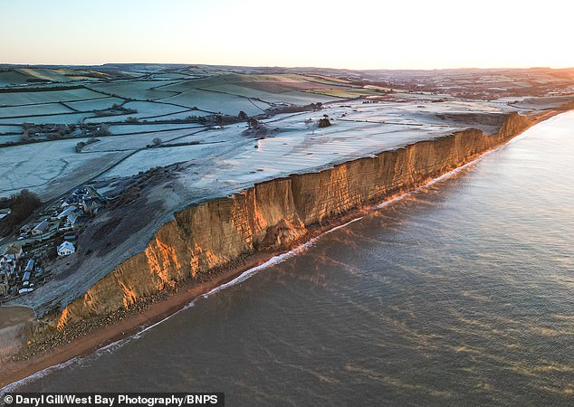 Early morning frost and mist as the sun rises over West Bay, Dorset