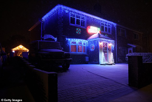 A house is illuminated with Christmas lights as snow falls. Temperatures reach -10 C this weekend in some parts of the UK with Amber weather warnings issued by the Met office