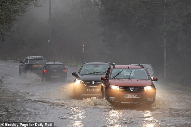 Cars navigating a flooded section of road in Watford, Hertfordshire, today