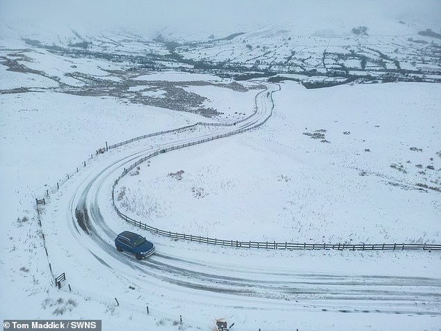 A car is driven through Derbyshire this morning as Mam Tor is blanketed in snow