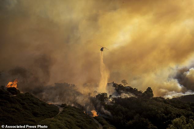 Water is dropped on the advancing Palisades Fire by helicopter