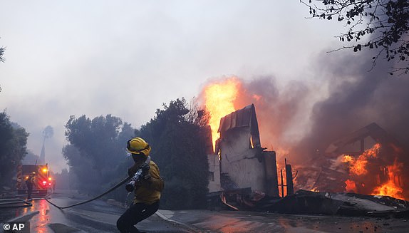 A firefighter battles the advancing Palisades Fire as it burns a structure in the Pacific Palisades neighborhood of Los Angeles, Tuesday, Jan. 7, 2025. (AP Photo/Etienne Laurent)