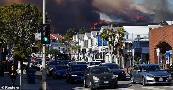 People evacuate, as smoke rises from a wildfire burning near Pacific Palisades on the west side of Los Angeles during a weather driven windstorm, in Los Angeles, California, January 7, 2025.  REUTERS/Daniel Cole     TPX IMAGES OF THE DAY