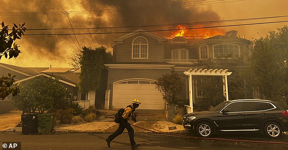 A residence burns as a firefighter battles the Palisades Fire in the Pacific Palisades neighborhood of Los Angeles Tuesday, Jan. 7, 2025. (AP Photo/Eugene Garcia)