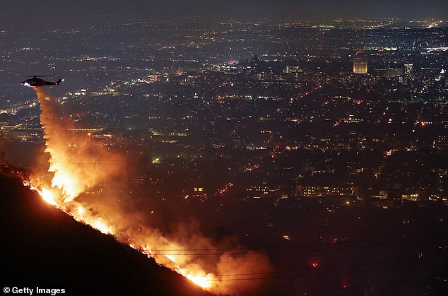 A fire service helicopter drops a huge stream of water on to the Sunset Fire above LA's Hollywood Hills