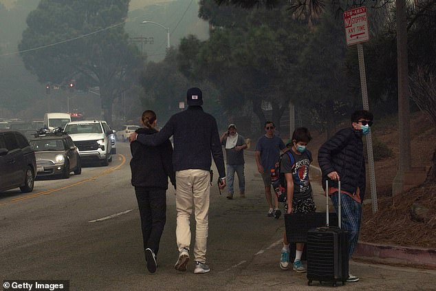 People evacuate along Sunset Boulevard as the Palisades Fire burns amid a powerful windstorm