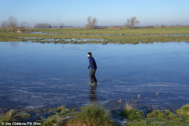 CAMBRIDGESHIRE: A person skates on a frozen flooded field in Upware, Cambridgeshire, on Friday