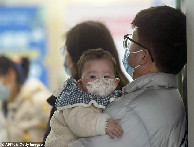 Scenes of hospitals overrun with people in face masks have made their rounds on social media. Pictured, A baby wearing a face mask waits with family members at the pediatric department of a hospital in Hangzhou, eastern China on January 6