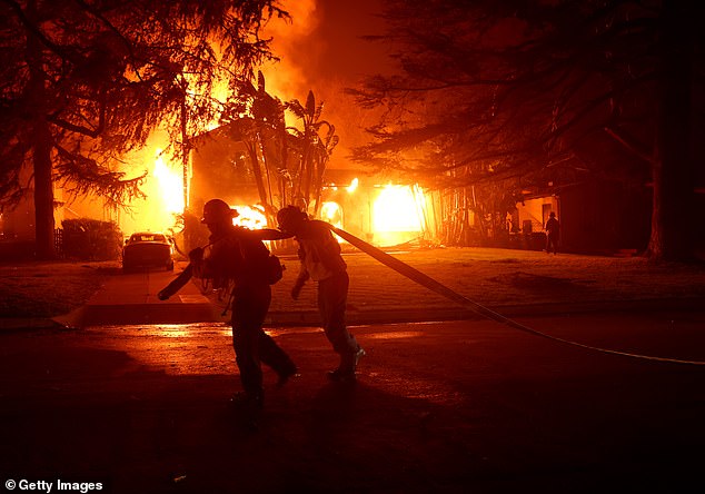 Residents of Mandeville Canyon and Brentwood are trying to flee to safety as the Palisades Fire has begun engulfing several celebrity-owned million dollar homes (pictured: Firefighters in Eaton)