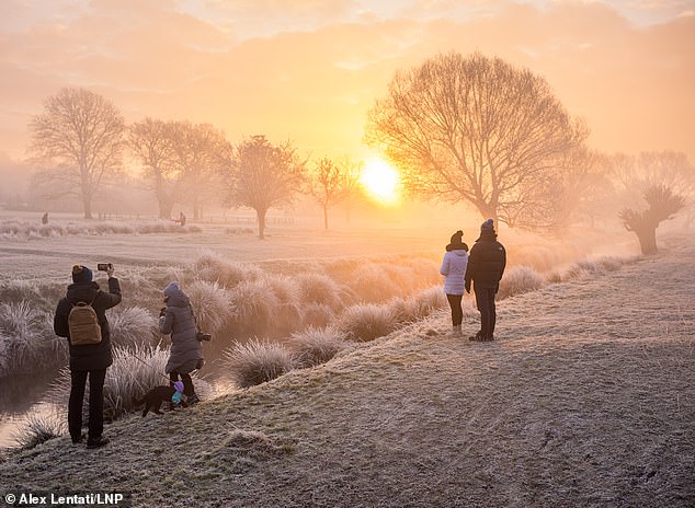 Walkers enjoy the freezing fog and icy weather in Richmond Park south-west London this morning as the Met Office warns of more snow and ice today