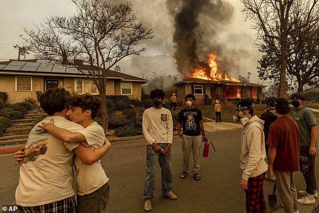 Residents embrace outside of a burning property as the Eaton Fire swept through Wednesday, January 8, 2025 in Altadena, California