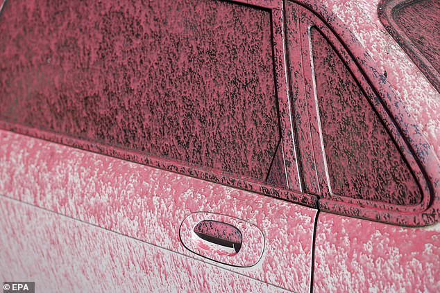 A car is covered in fire retardant in the Pacific Palisades neighborhood in Los Angeles, California