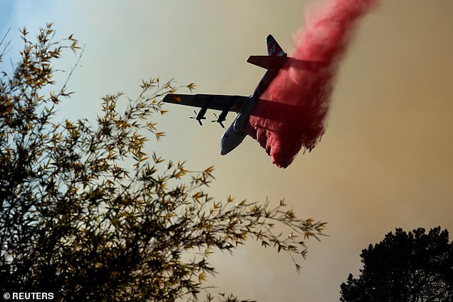 An aircraft drops water retardant to contain the Palisades Fire, one of simultaneous blazes that have ripped across Los Angele