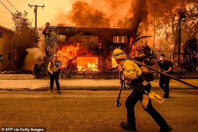 Firefighters fight a blaze as a building burns during the Eaton fire in the Altadena area of Los Angeles county, California