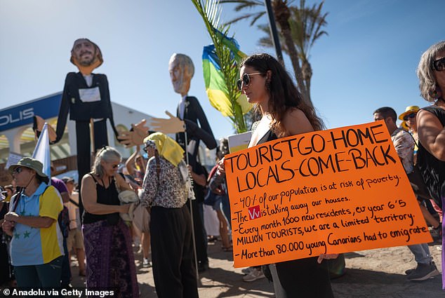 Tenerife locals hold placards raising concerns about the impact of mass tourism, October 2024