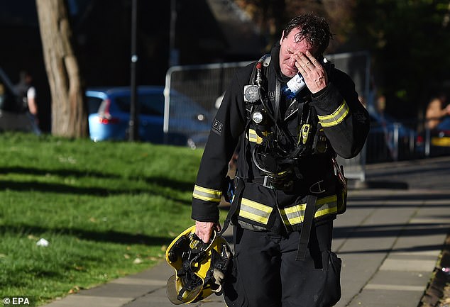 More than 150 firefighters have been left with chronic health conditions after tackling the deadly Grenfell Tower fire. Pictured: A fireman reacts after battling the blaze