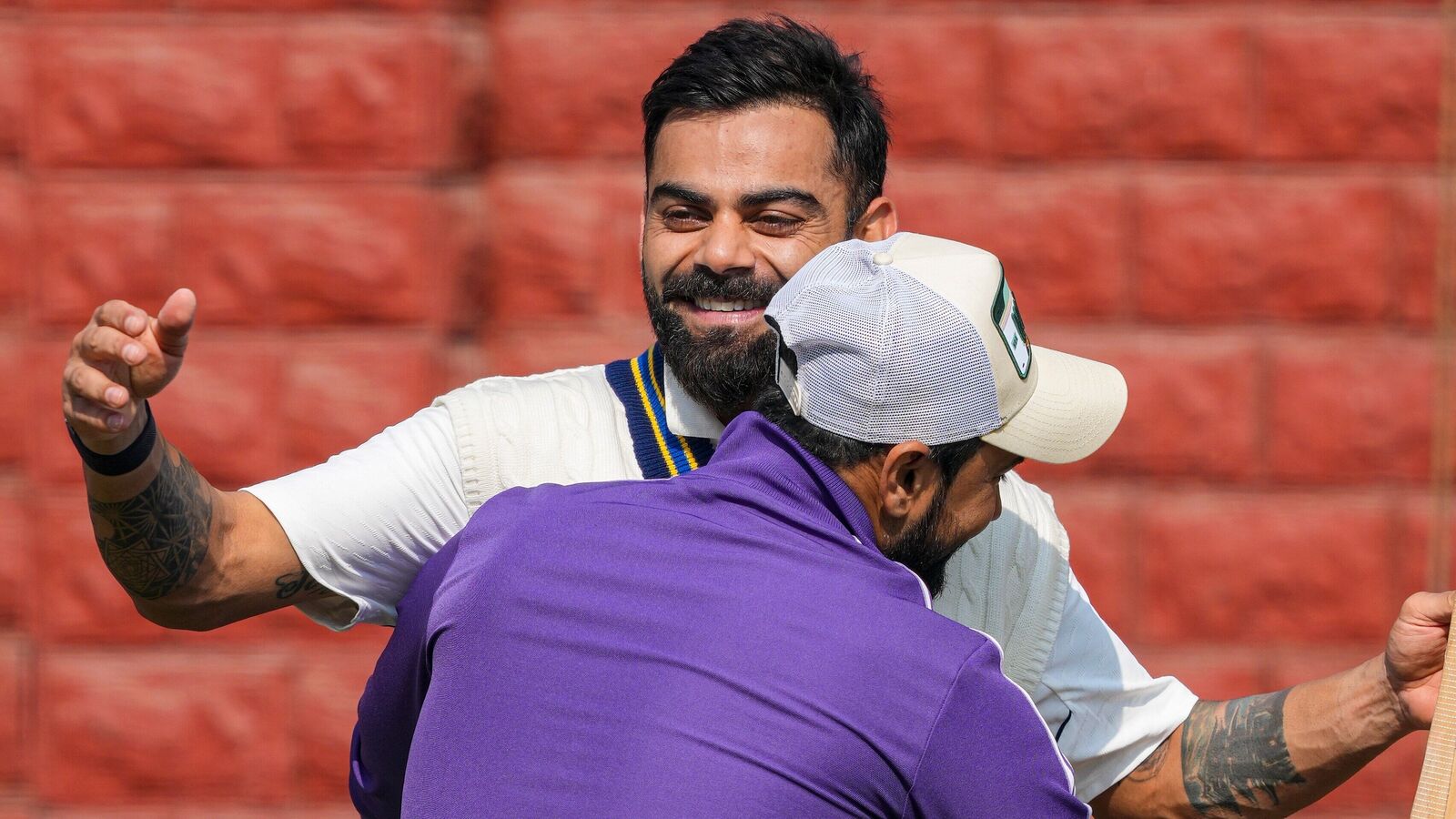 Virat Kohli hugs his former Delhi cricket mate Shavez during a training session at the Arun Jaitley Stadium.