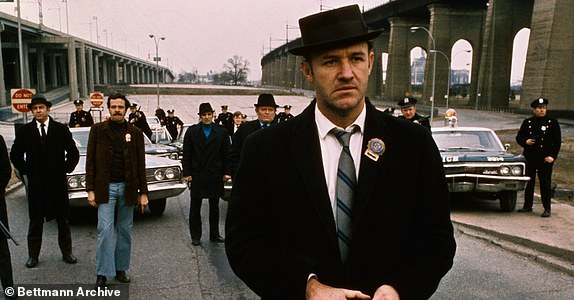 Policeman Gene Hackman is shown in this movie still walking toward the camera. He is holding a gun in his hands with policemen and police vehicles in the background. It was in this movie The French Connection that Gene Hackman won "Best Actor." The movie itself won "Best Picture."