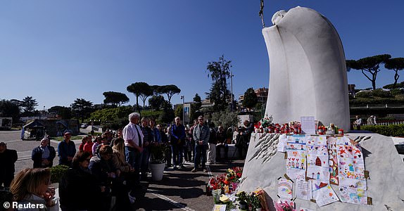 People pray near the statue of late Pope John Paul II outside Gemelli Hospital where Pope Francis is admitted for treatment, in Rome, Italy, March 5, 2025. REUTERS/Remo Casilli