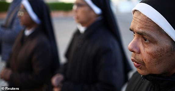 Nuns pray near the statue of late Pope John Paul II outside Gemelli Hospital, where Pope Francis is admitted for treatment, in Rome, Italy, March 4, 2025. REUTERS/Guglielmo Mangiapane