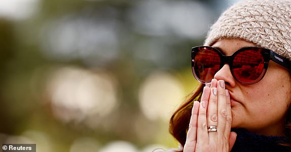 A woman prays next to the statue of late Pope John Paul II outside Gemelli Hospital, where Pope Francis is admitted for treatment, in Rome, Italy, March 4, 2025. REUTERS/Yara Nardi