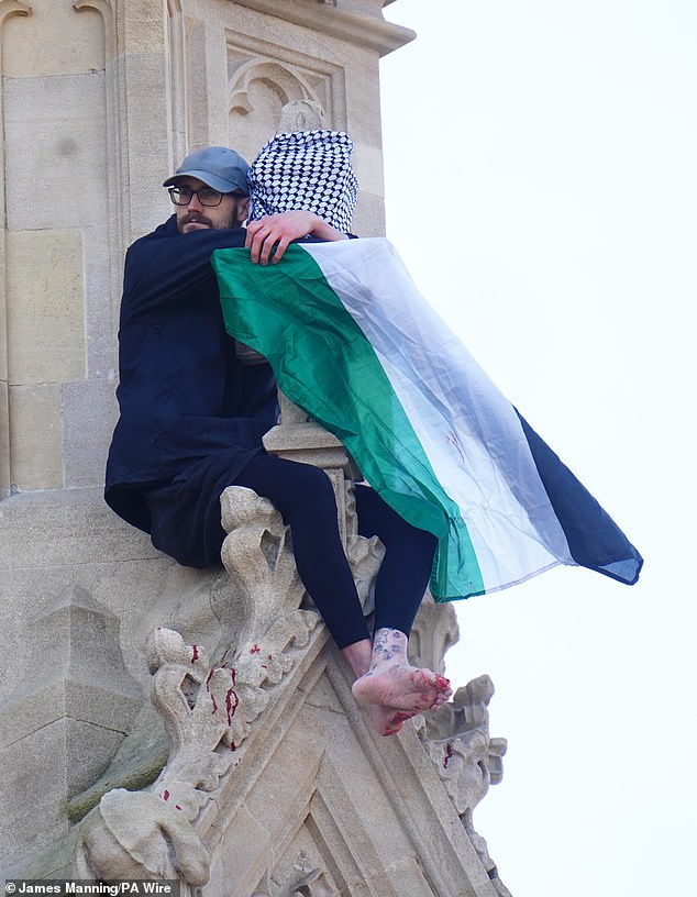 The protester clutches onto a Palestinian flag as blood pours from his feet onto parts of the tower