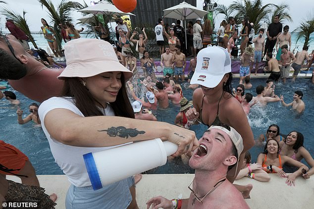 A man drinks from a bottle at a beach club in Cancun