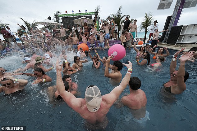 People dance in a pool party at a beach club during the spring break in Cancun