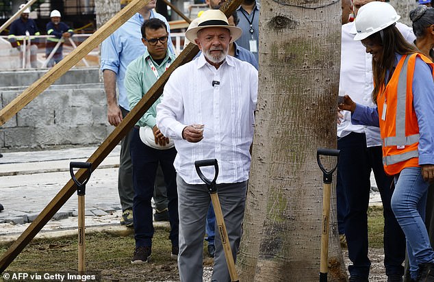 Brazilian President Luiz Inacio Lula da Silva (C) is pictured before putting fertilizer on a Samauma tree (Ceiba pentandra), typical of the Amazon rainforest