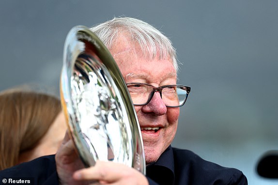 Horse Racing - Cheltenham Festival - Cheltenham Racecourse, Cheltenham, Britain - March 13, 2025 Former football manager Alex Ferguson celebrates with a trophy after Caldwell Potter ridden by Harry Cobden won the 14:00 Jack Richards Novices' Limited Handicap Chase REUTERS/Matthew Childs