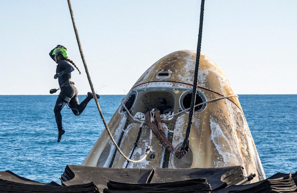 A SpaceX support team member is seen airborne while working to lift the SpaceX Dragon capsule onto a recovery vehicle following its landing off the coast of Florida.