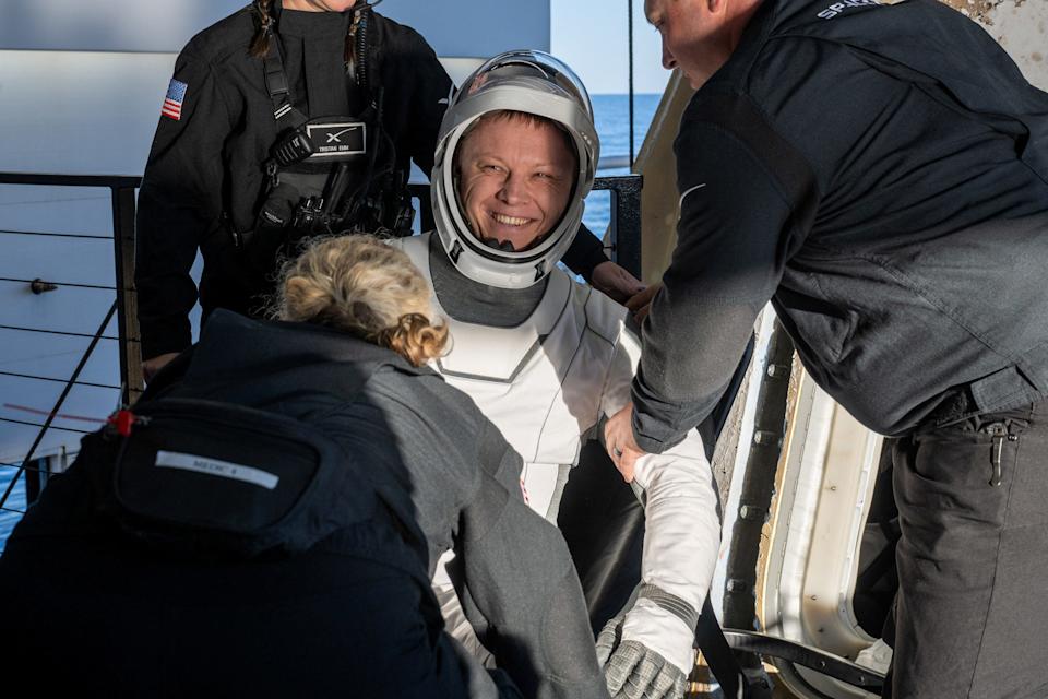 Roscosmos cosmonaut Aleksandr Gorbunov is helped out of a SpaceX Dragon spacecraft.