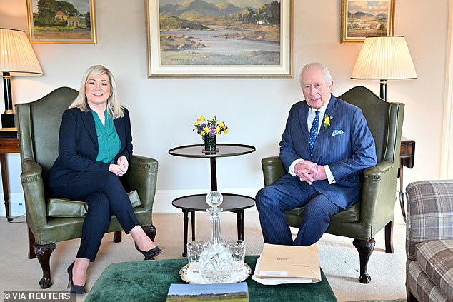 Charles pictured sitting down with the First Minister of Northern Ireland
