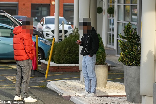 Asylum seekers pictured outside a migrant hotel in Altrincham, Greater Manchester last year