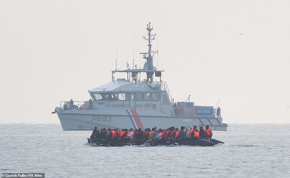 A French coastguard boat is seen monitoring a boat packed with people on Saturday morning in the sea off the coast of France