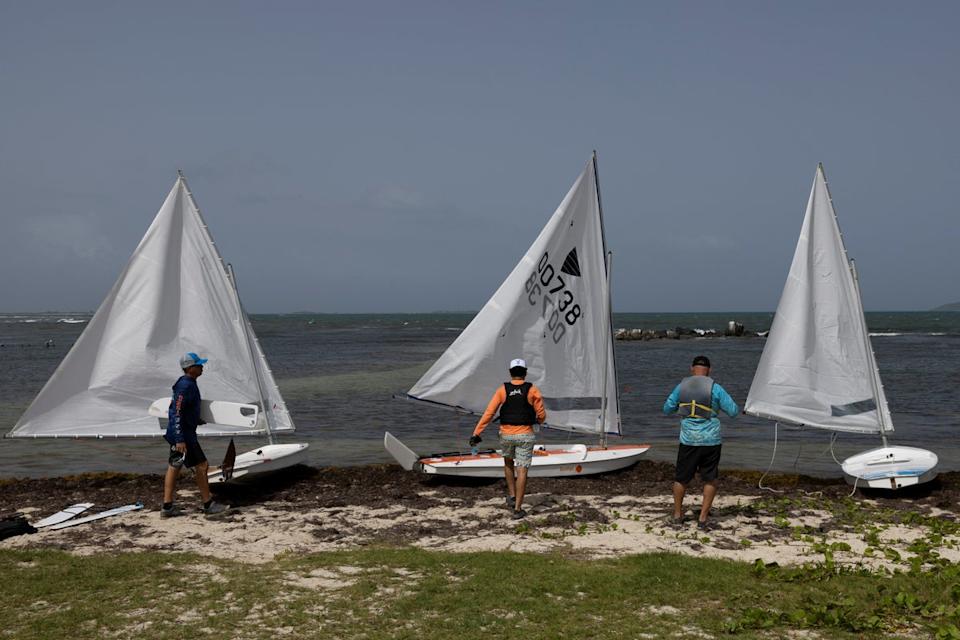 Men prepare to launch their sailboats on a beach covered in sargassum seaweed washed ashore (REUTERS)
