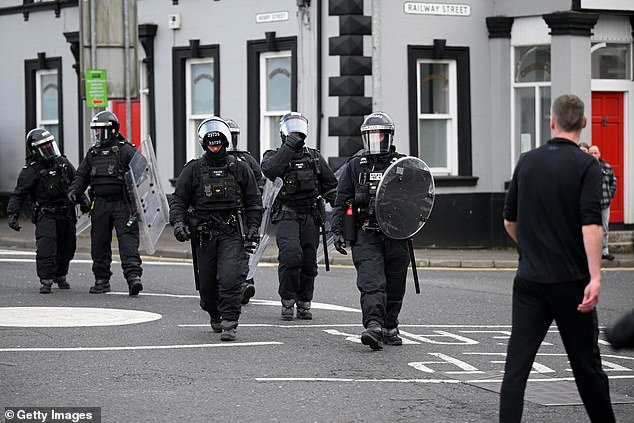 Residents look on as PSNI riot squad officers form a blockade on Harryville bridge to stop potential rioters from accessing the Clonavon terrace area