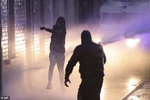 Protesters try to throw items at the police who use water canons to clear them in Ballymena