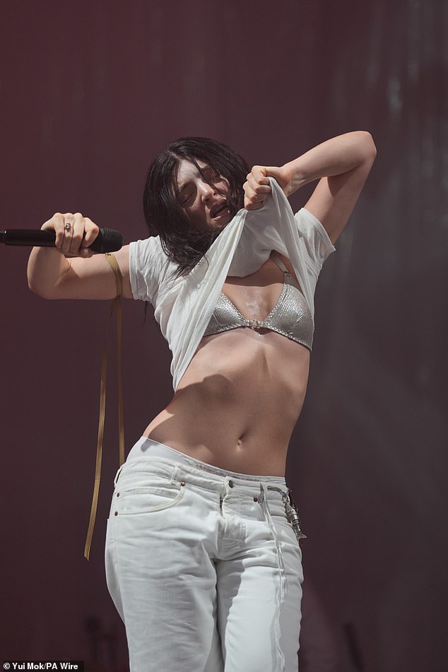 Lorde flashed her incredible physique as she performed on stage, lifting her top to expose her bra