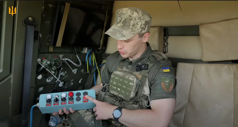 A Ukrainian operator holds a switchboard with five switches and a launch button.
